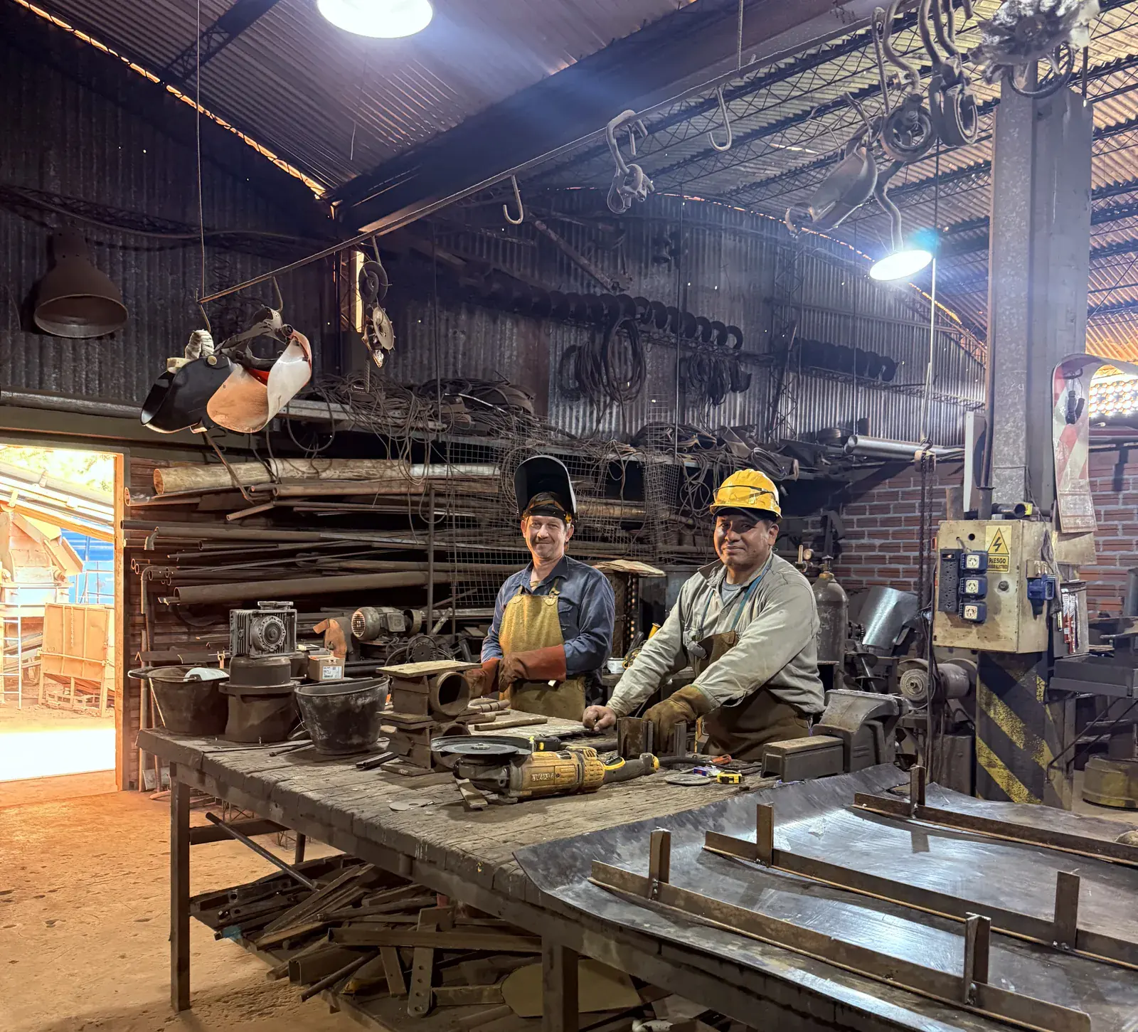 Dos operarios de la planta en el taller, junto al banco de trabajo